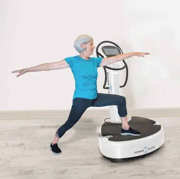 Older woman using power plate in physical therapy setting pic
