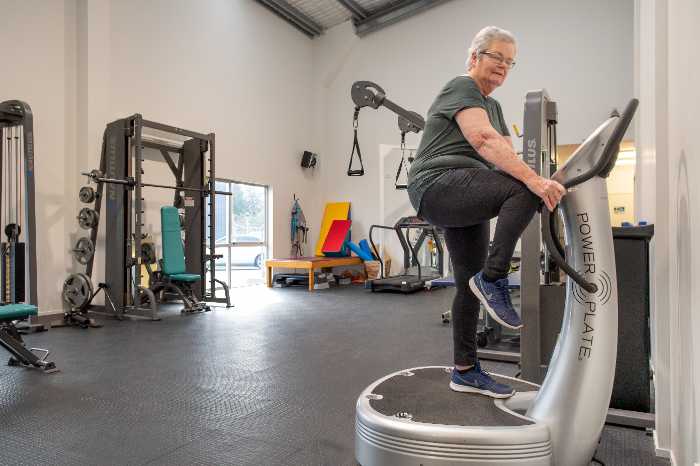 Older woman 2 using vibration technology for balance in physical therapy setting
